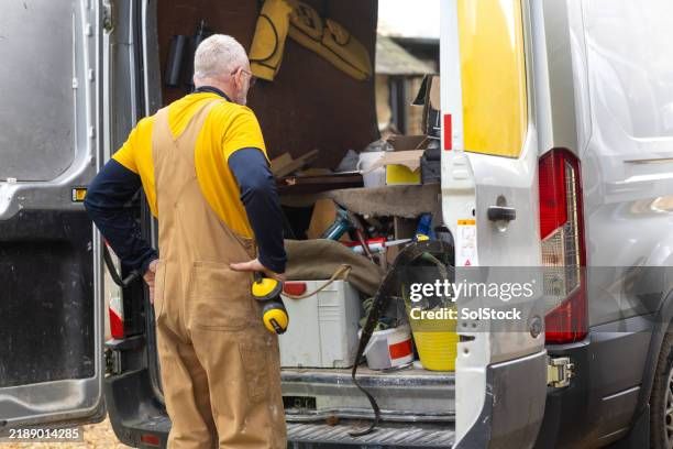 Handwerker blickt in einen voll beladenen Transporter mit Werkzeug.